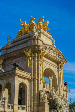 Golden statue of aurora in a chariot pulled by four horses atop the cascada monumental fountain in parc de la ciutadella barcelona spain with blue sky background