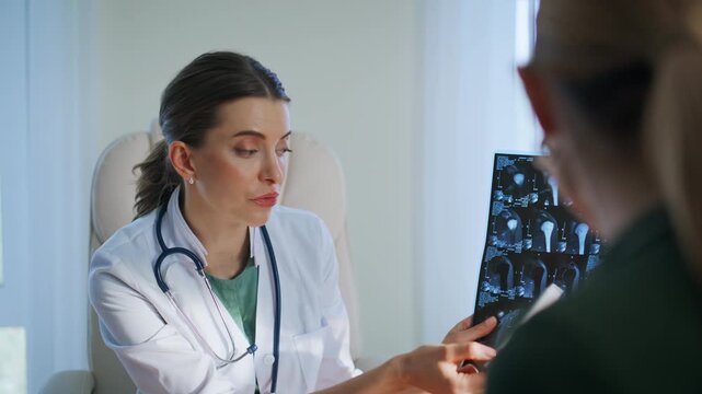 Dedicated doctor reviewing x-ray image with patient bright clinic room closeup