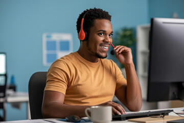 Happy smiling African American male customer support agent with headset working at computer in modern office service help desk center concept professional employee.
