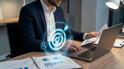 Businessman in a modern office analyzing data on a laptop with digital target icons, surrounded by papers and graphs, conveying a sense of strategy and productivity.