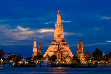 Naklejka premium Majestic Wat Arun illuminated at dusk along the Chao Phraya River in Bangkok
