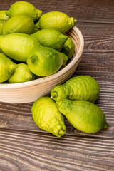 Fresh green lemons in a wicker bowl on wood
