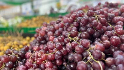 Close-up view of fresh red grapes displayed in a pile at a local fruit market. Juicy ripe grapes...