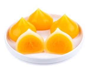 Plate of teardrop-shaped orange and white sweets, one split in half, on a white plate against a white background