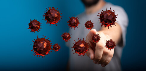 Conceptual image of a man pointing at airborne Coronavirus cells, illustrating the spread of infection, highli