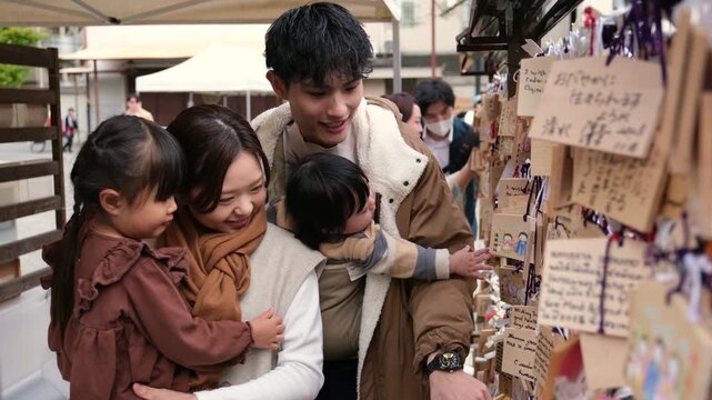 Happy asian family enjoying their vacation together at a temple writing wishes on ema wooden plaques