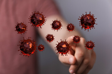 Close-up of a hand pointing at 3D rendered coronavirus cells to represent concept of infection, contamination,