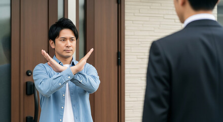訪問販売お断りのメタファー、両手でバツを作り営業を明確に拒否する日本人男性とコピースペース