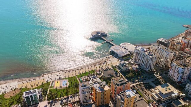 Aerial drone view of the iconic circular Rotonda building extending over the turquoise waters of the Adriatic Sea in Durres, Albania