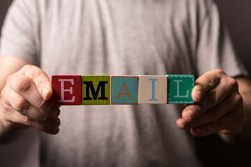 Person holding wooden blocks spelling out the word 'email', a visual representation of electronic messaging and