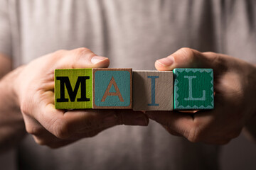 Close-up of hands holding wooden blocks with the word 'MAIL', symbolizing communication, message, delivery, and