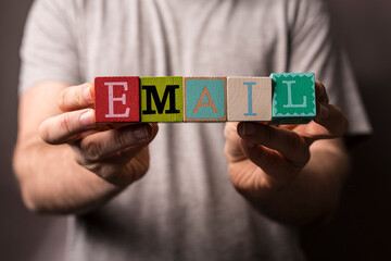 Person holding colorful letter blocks spelling out the word email. Concept of online communication, message send