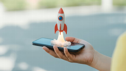 Hand holds smartphone with toy rocket launching from its screen, symbolizing innovation and creativity. scene conveys excitement and futuristic technology