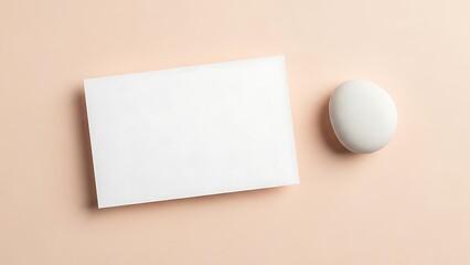 Minimalist Composition White Textured Card and Smooth Oval Stone on Pastel Backdrop