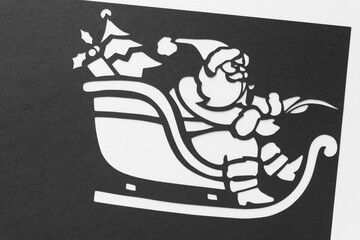 black and white stencil of Santa Claus on a sleigh machine-cut from black paper
