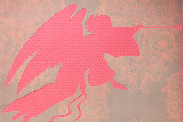 trumpeting angel machine-cut from decorative coral red paper with pattern placed on a decor sheet