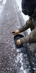 Winter Worker Spreading Granules Across a Driveway