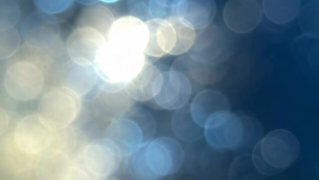 video shows an abstract background of blurred circles in shades of blue and white creating a bokeh effect. Premium bokeh background for wallpaper, banner and poster.