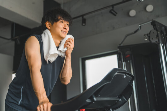 Young Asian man doing aerobic exercise on a walking machine in a sports gym