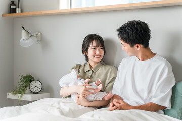 Mom and dad holding a baby in their bedroom (parenting)