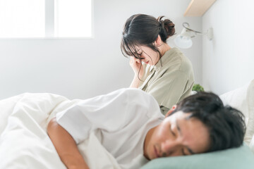 Obraz premium A woman suffering from sleep deprivation and a man sleeping in bed