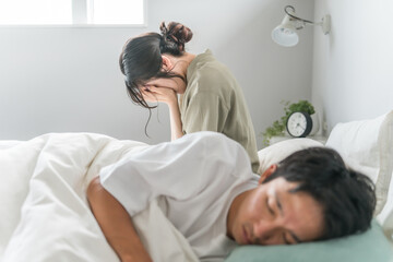 A man sleeping with a woman suffering from sleep deprivation in bed (insomnia, stress, sleep disturbance)