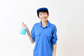清掃用スプレーを持つ作業服のアジア人の中高年女性