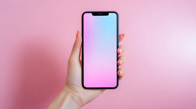 Hand holding smartphone with colorful screen on pink background.