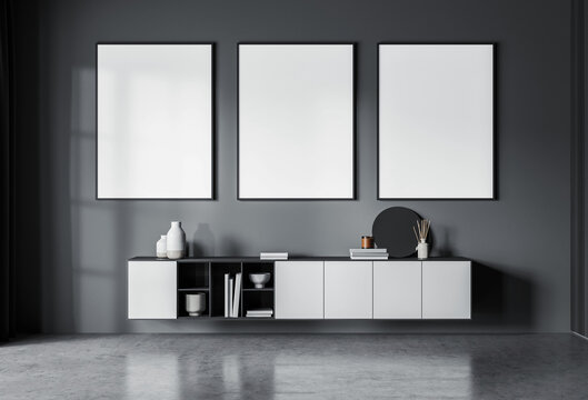 Contemporary interior scene with three vertical blank posters above a floating sideboard, minimalist decor, on dark gray wall background. 3D Rendering