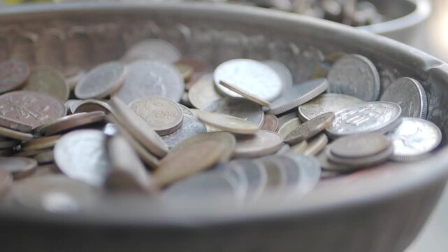 Exploring different coins in a metal bowl
