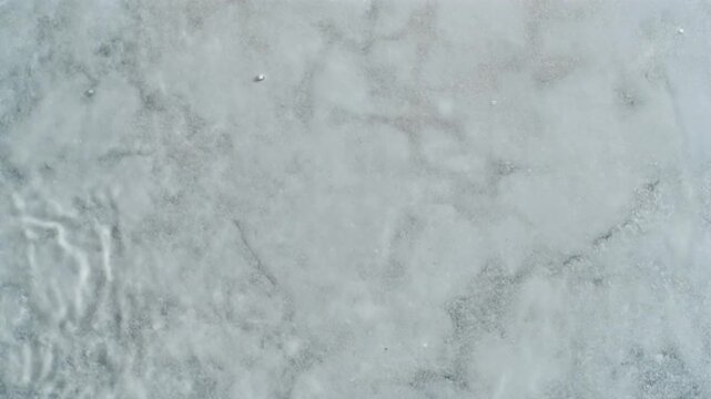Detailed Aerial View Capturing Abstract Patterns and Subtle Ripples on a Frozen Water Surface in a Cold Natural Environment with negative space b roll for advertising and news