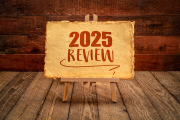 2025 year review - easel sign with antique paper against rustic wood, end of year business concept