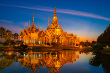 Fototapeta premium The beautiful golden buddhist temple with water reflect shadow in sunset time at Nakhon Ratchasima Thailand