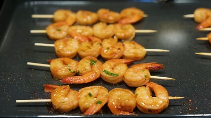 Shrimp skewers cooking on a grill with spices in a home kitchen setting