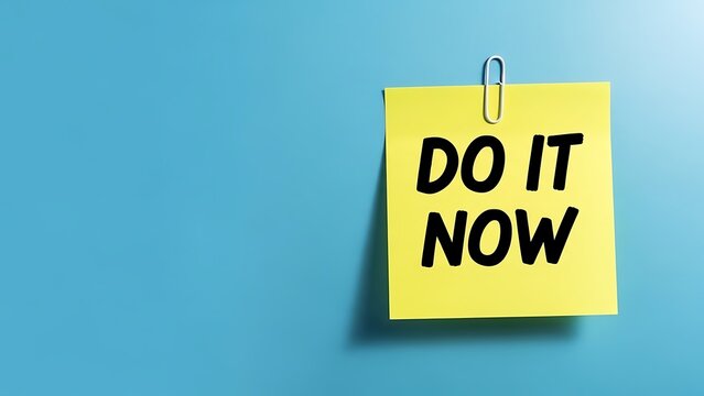 Yellow sticky note with black text reading do it now clipped against a solid blue background