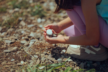 Little Girl Collecting Stones Like Little Treasures Outdoors. Child appreciating the little joys in...