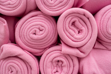 Close up of pink fleece fabric rolls stacked together. several rolls of bright pink soft fleece or flannel fabric. Texture detail of textile material used for blankets, winter clothing. © Wongsakorn