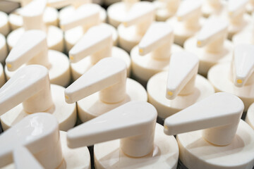 Row of white plastic pump dispensers for bottles close up. Industrial production of packaging for cosmetic and hygiene products.