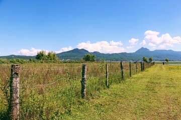 Naklejka premium Blue Sky White Clouds Meadow Fence Landscape