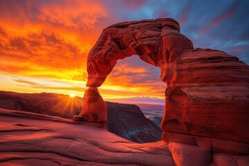 sunrise behind a natural red sandstone arch over a vast canyon, glowing colorful sky and radiant sunburst creating a dramatic awe-inspiring scene