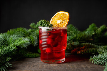 Tasty christmas cocktail with cranberry decorated with dried orange slice. Shallow depth of field. Selective focus.