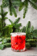 Red christmas cocktail with cranberry juice on the fir branches background. Christmas mood. Selective focus. 