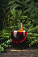 Mulled wine with orange, cranberry and cinnamon in fir forest setting. Selective focus.