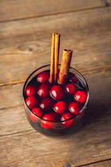 Mulled wine with orange, cranberry and cinnamon on rustic wooden background. Selective focus.