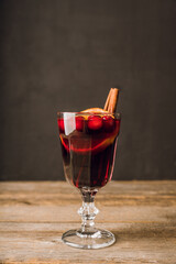 Mulled wine with orange, cranberry and cinnamon on rustic wooden background. Selective focus.