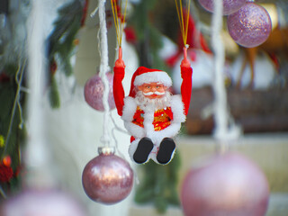 Santa Claus toy close-up on the background of a blurred Christmas tree
