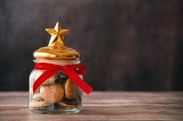 Glass container with Christmas star filled with sweets on wooden table