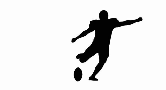 Silhouette of an American football player kicking the ball.