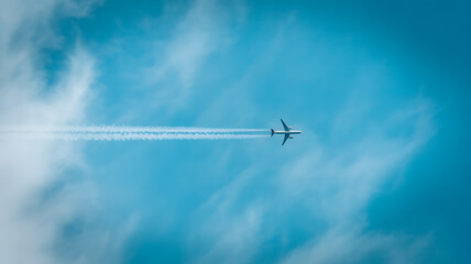 Airplane flying in a clear blue sky leaving a contrail behind