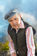 An elderly pensioner cultivates his garden with a hoe in the fall